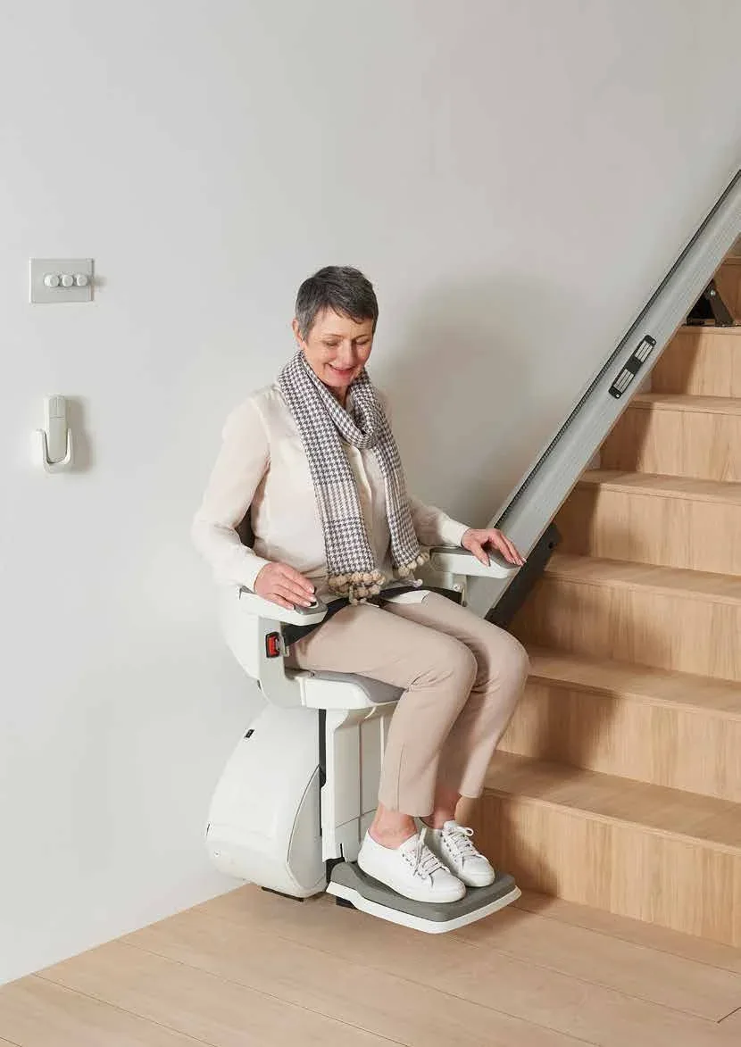 Utilisatrice souriante assise sur un monte-escalier HomeGlide